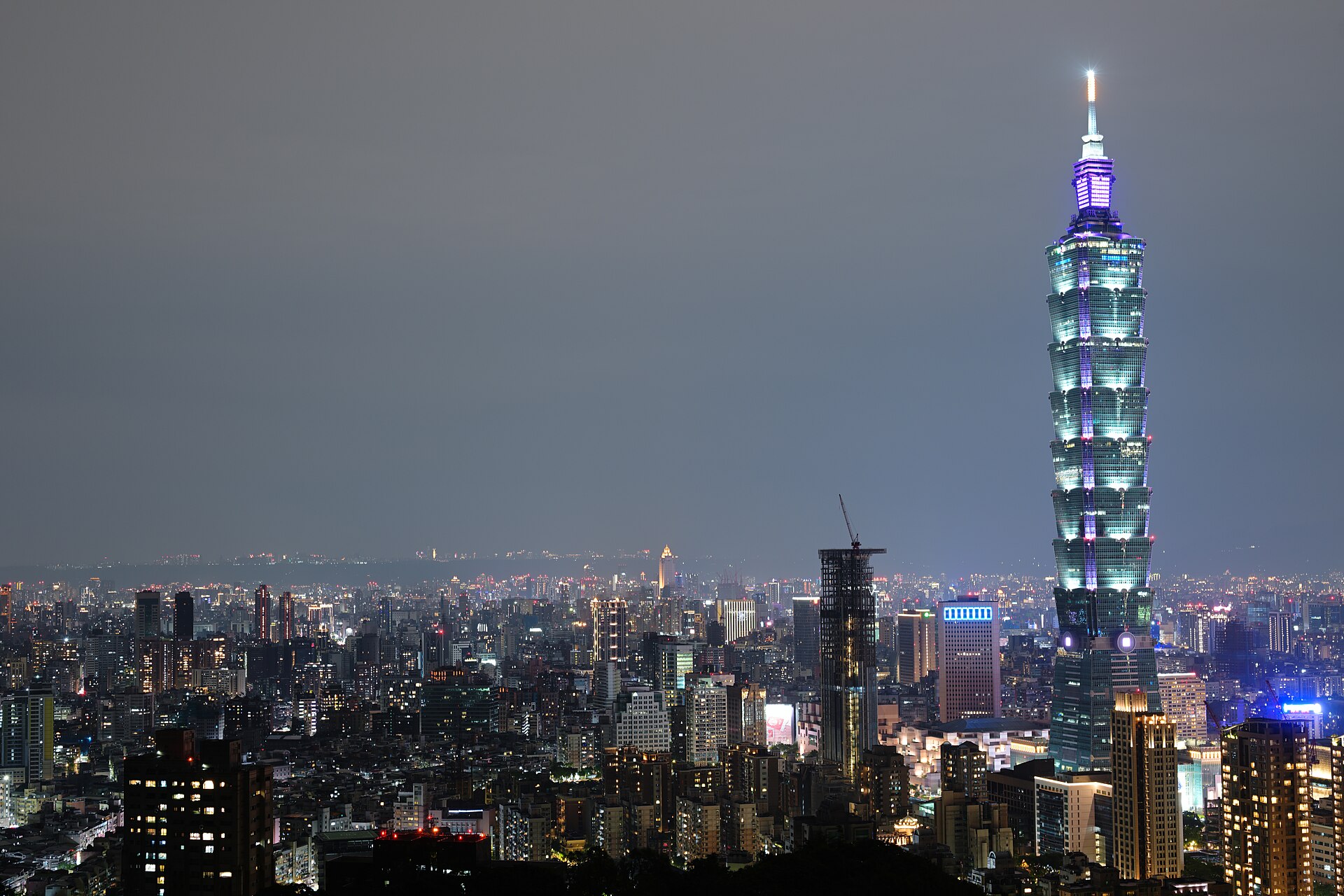 Taipei 101 lit at night above the city skyline